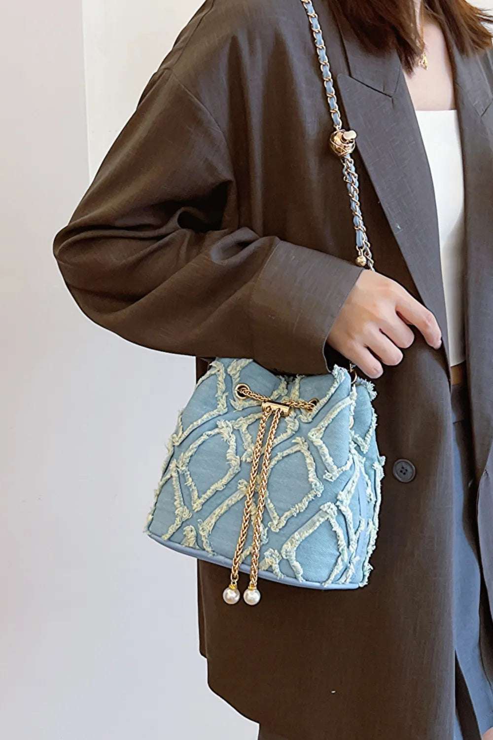 Chain Drawstring Raw Edge Denim Bucket Bag - Premium Crossbody Bag from Trendsi - Just $34.99! Shop now at Handbags Specialist Headquarter